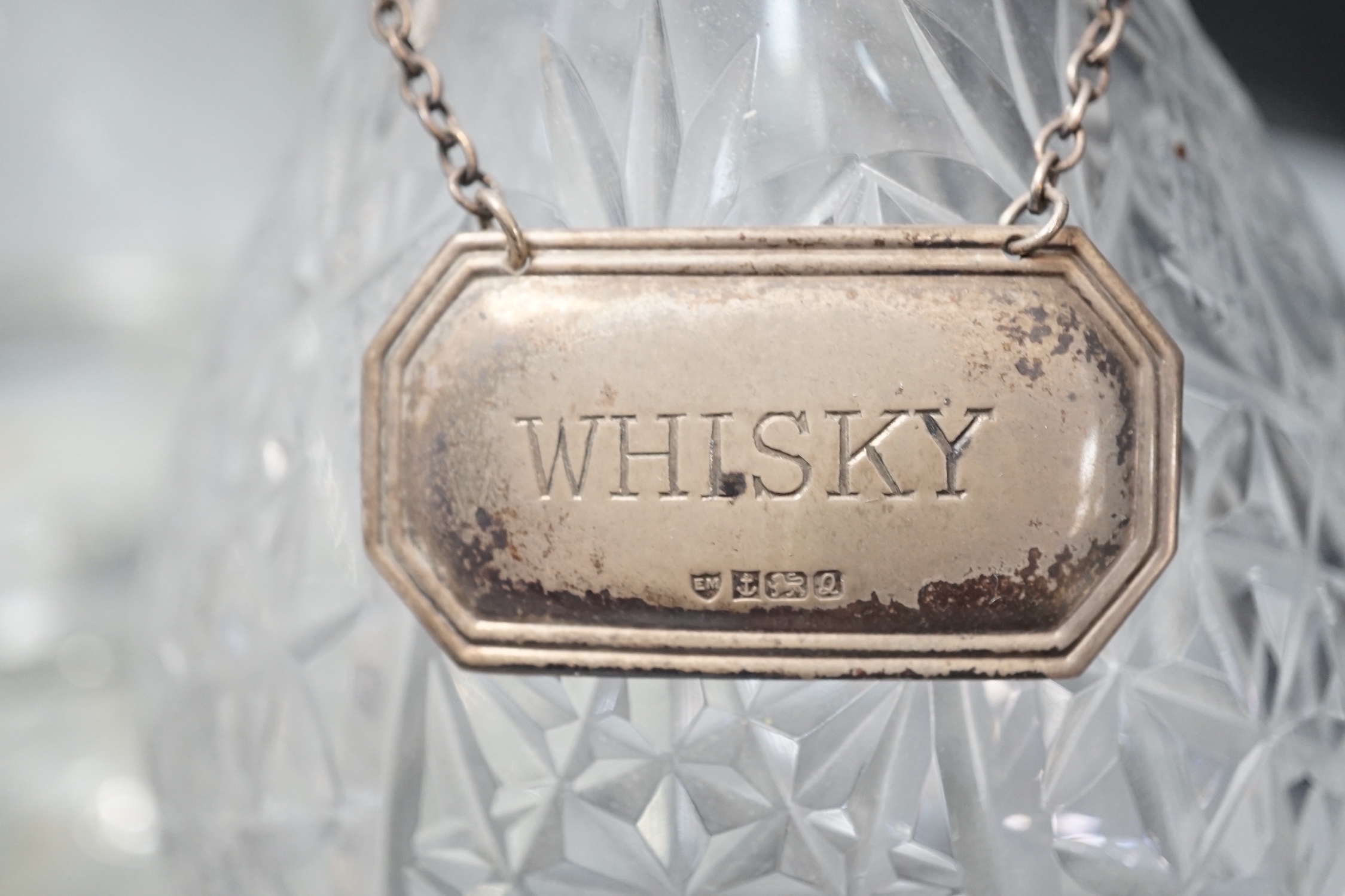 A silver topped decanter together with two other assorted decanters, a silver whisky label and a silver plated basket